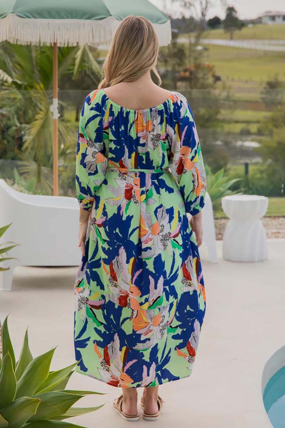 A model wearing the Ava Dress in colour Getaway (Blue), from the back