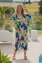 A model wearing the Ava Dress in colour Getaway (Blue), from the front, showing the whole outfit