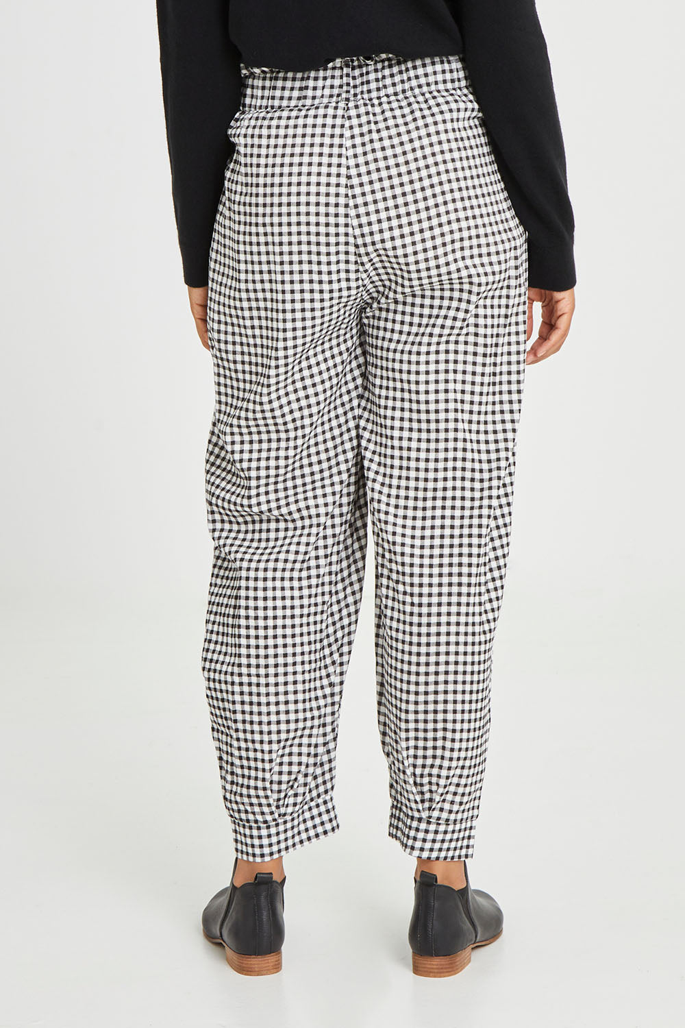 Model Olivia wearing size S of the Archer Pant in colour Nightcheck (Blue), from the back