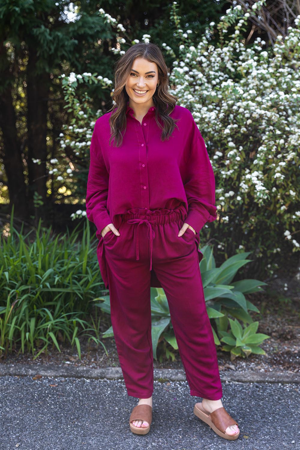A model wearing the Olivia Pant in colour Deepplum (Pink), from the front, showing the whole outfit