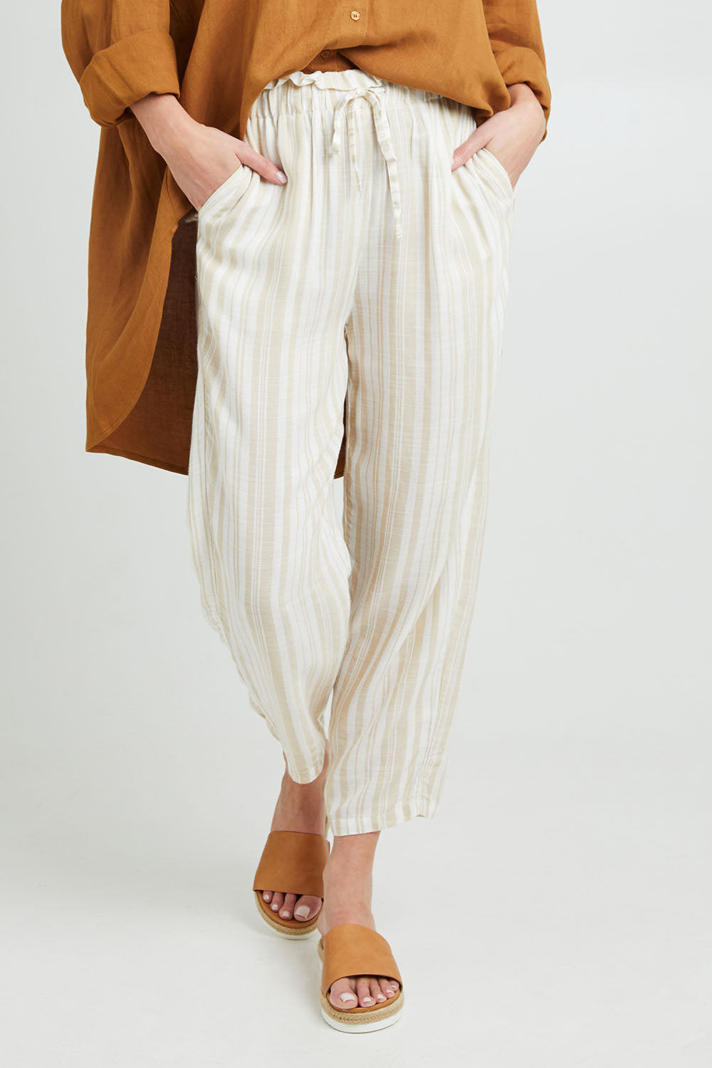 Model Grace wearing size S of the Olivia Pant in colour Beige, from the front, cropped image