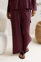 A model wearing the Eden Cotton Blend Pants in colour Plum (Red), from the front, cropped image