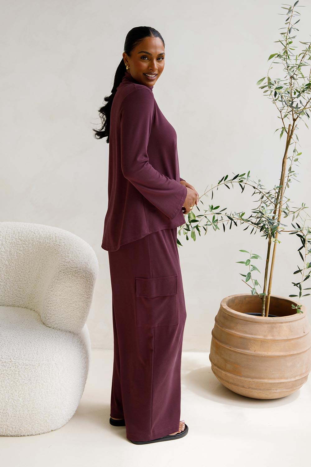 A model wearing the Eden Cotton Blend Pants in colour Plum (Red), from the front, showing the whole outfit