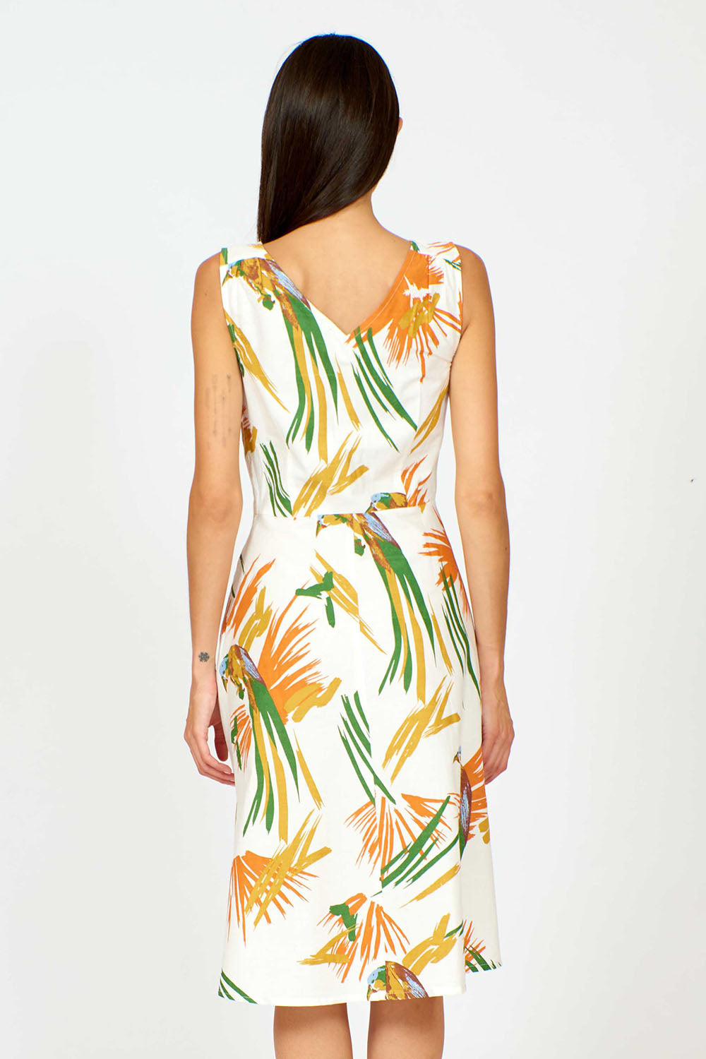 A model wearing the Harriet Dress in colour Parrot (White), from the back