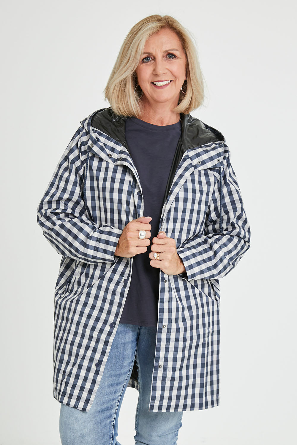 Model Sandy wearing size S of the Rosie Raincoat in colour Navychequ (Blue), from the front, cropped image