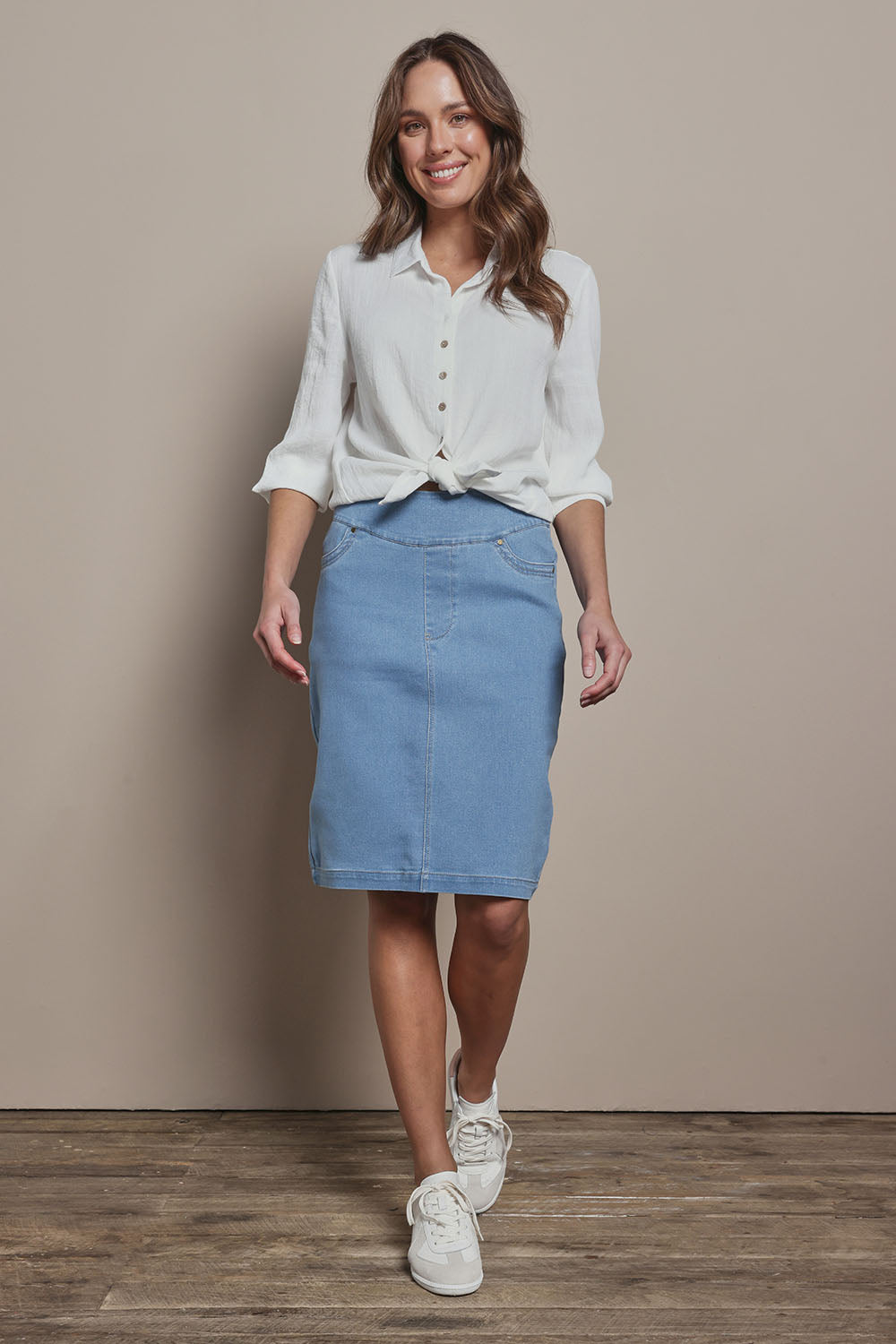 Model Madeline wearing size 10 of The Pull On Denim Skirt in colour Lightdenim (Blue), from the front, showing the whole outfit