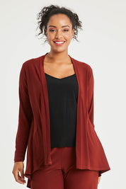 Model Noli wearing size 14 of The Recycled Flounce Cardigan in colour Terracotta, from the front, cropped image