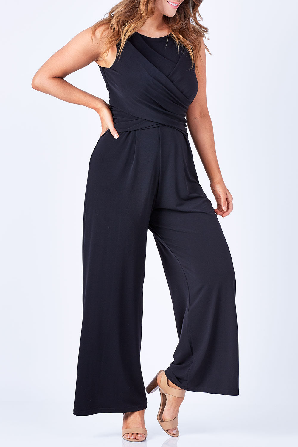 Model Laura wearing size 12 of The Cross Waist Jumpsuit in colour Black (Black), from the front, cropped image