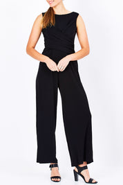 Model Maddy wearing size 10 of The Cross Waist Jumpsuit in colour Black (Black), from the front, cropped image