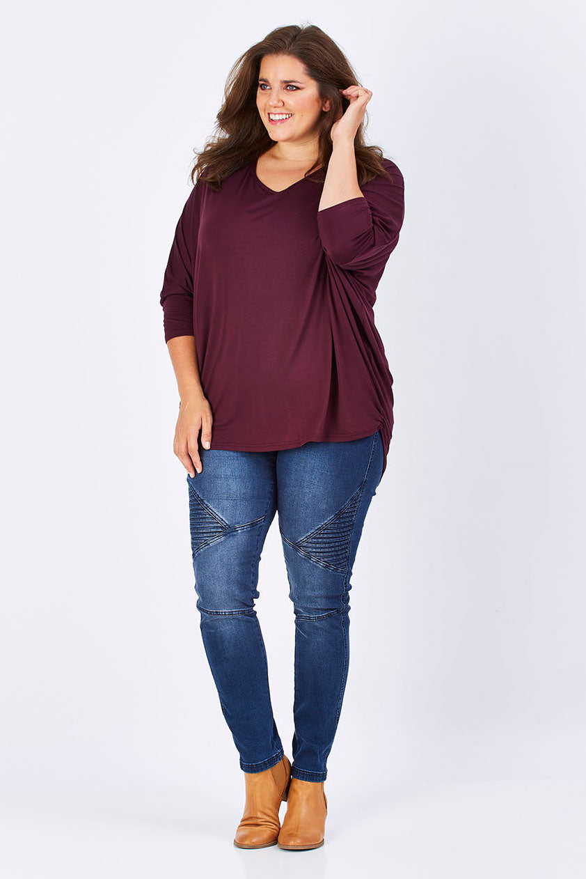 Model Mae wearing size 18 of The V Neck Side Drape Tee in colour Wine (Purple), from the front, showing the whole outfit
