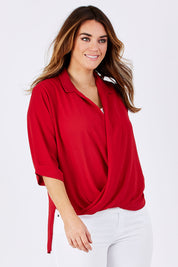 Model Laura wearing size 12 of The Cross Over Blouse in colour Red (Red), from the front, cropped image