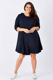 Model Mae wearing size 18 of The Long Sleeve Swing Dress in colour Navy (Blue), from the front, showing the whole outfit