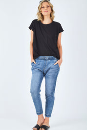 Model Chelsea wearing size 10 of The Pull On Jogger Jean in colour Denim (Blue), from the front, showing the whole outfit