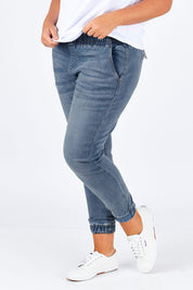 Model Fiona wearing size 16 of The Pull On Jogger Jean in colour Denim (Blue), from the front, cropped image