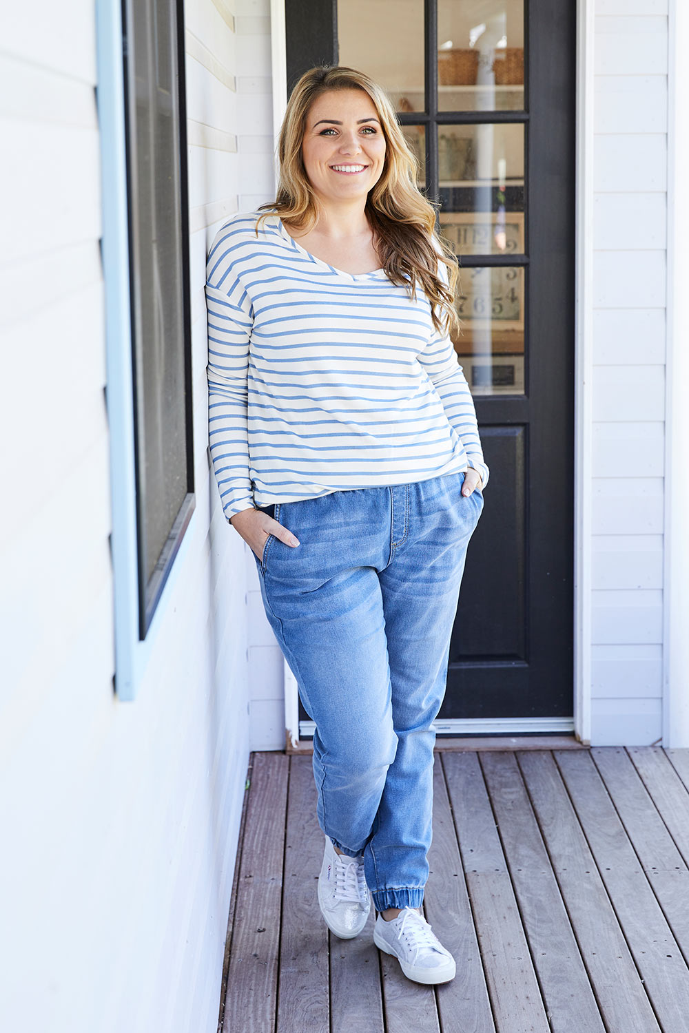 A model wearing size 14 of The Pull On Jogger Jean in colour Denim (Blue), from the front, showing the whole outfit