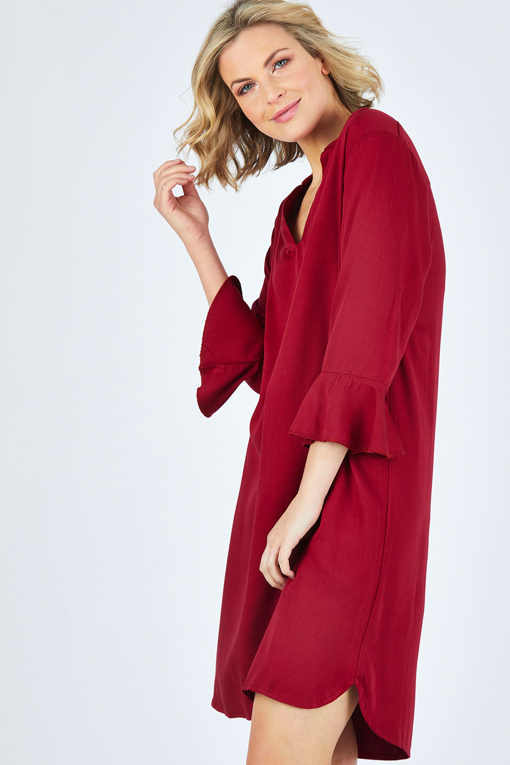 Model Chelsea wearing size 10 of The Flute Sleeve Dress in colour Cherry (Red), from the front, cropped image