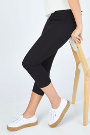 Model Chelsea wearing size 10 of The Cropped Skinny Pull On Jean in colour Black (Black), from the front, cropped image