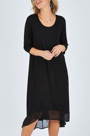Model Chelsea wearing size 10 of The Chiffon Trim Dress in colour Black (Black), from the front, cropped image