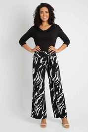 Model Pamela wearing size 10 of The Printed Travel Pant in colour Abstract (Black), from the front, showing the whole outfit