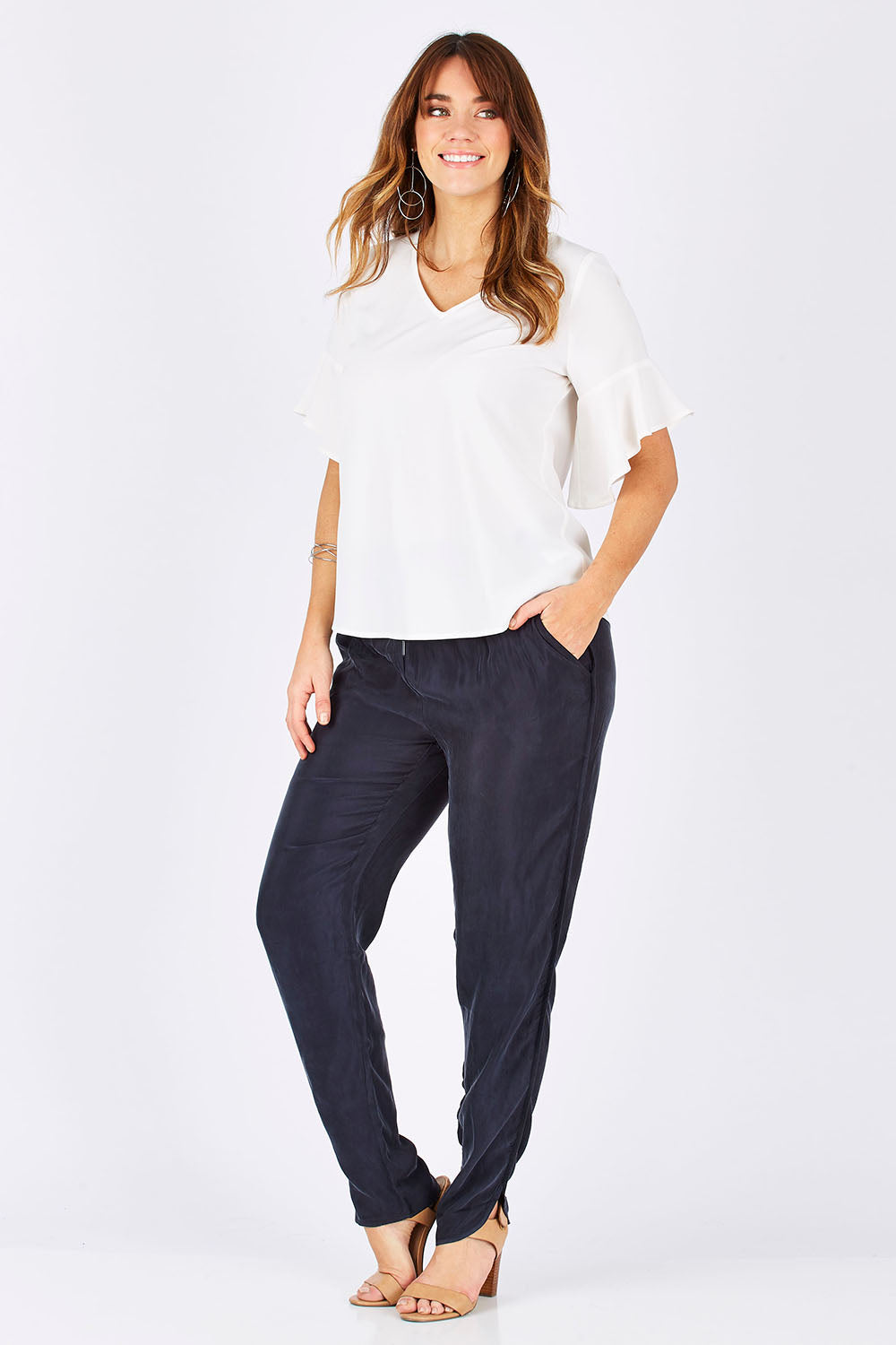 Model Laura wearing size 14 of The Curve Hem Pant in colour Ink (Blue), from the front, showing the whole outfit