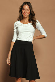 Model Madeline wearing size 10 of The Ponte Flip Skirt in colour Black (Black), from the front, cropped image
