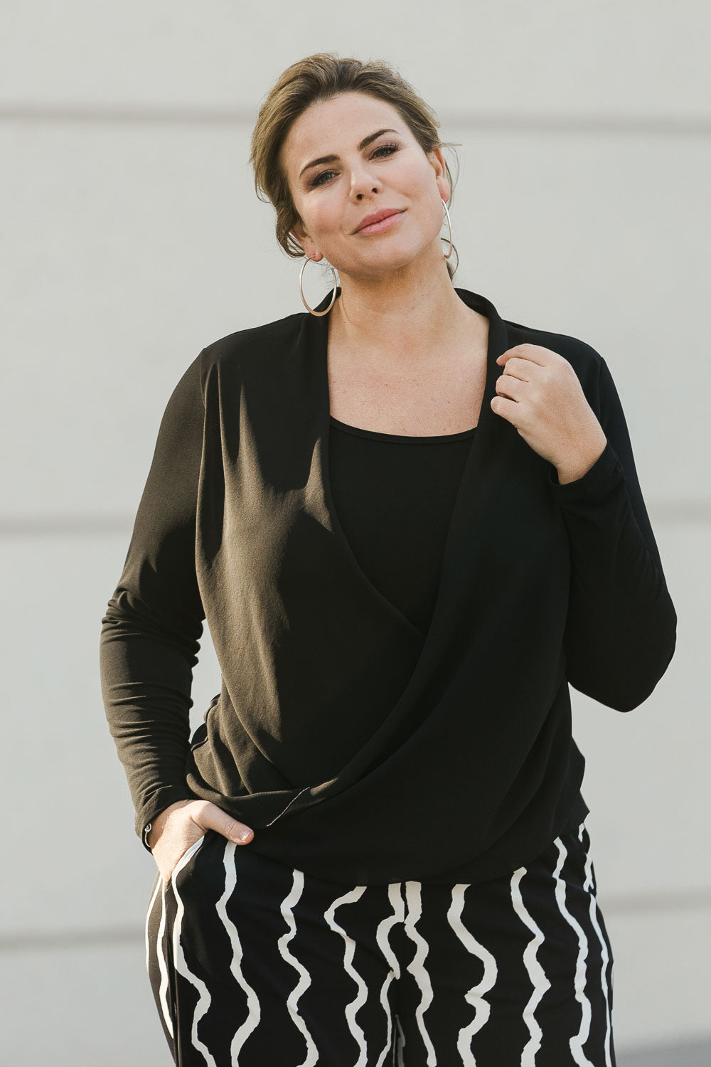 Model Fiona wearing size 16 of The Faux 2 Piece Crossover Top in colour Black (Black), from the front, showing the whole outfit