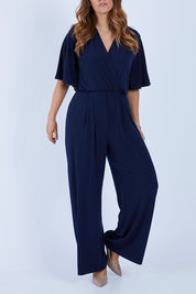 Model Laura wearing size 12 of The Bell Sleeve Jumpsuit in colour Navy (Blue), from the front, cropped image