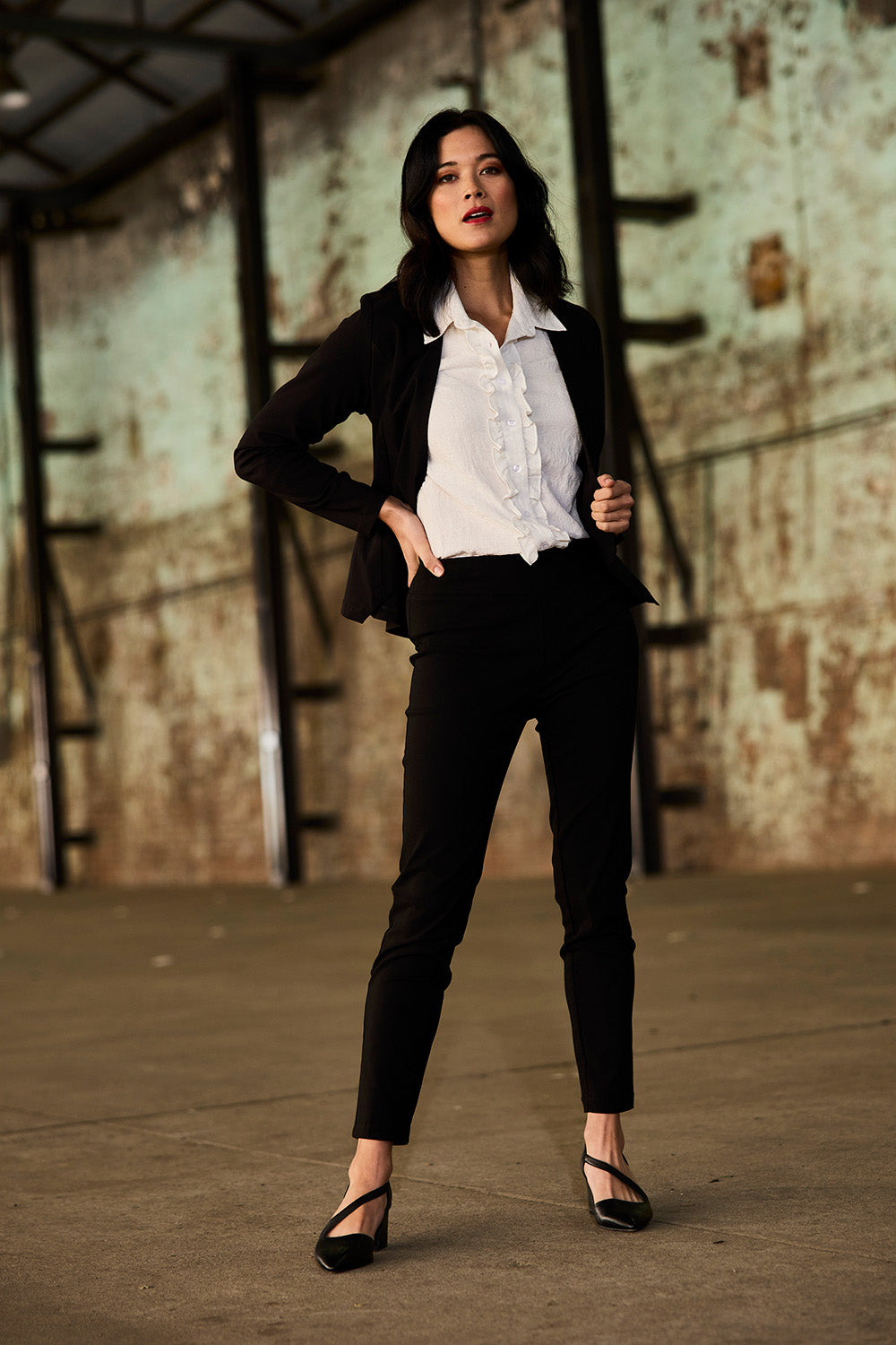 Model Miranda wearing size 10 of The Stretch Career Pull On Pant in colour Black (Black), from the front, showing the whole outfit