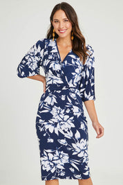 Model Madeline wearing size 10 of The Printed Knot Waist Detail Dress in colour Navyfleur (Blue), from the front, cropped image
