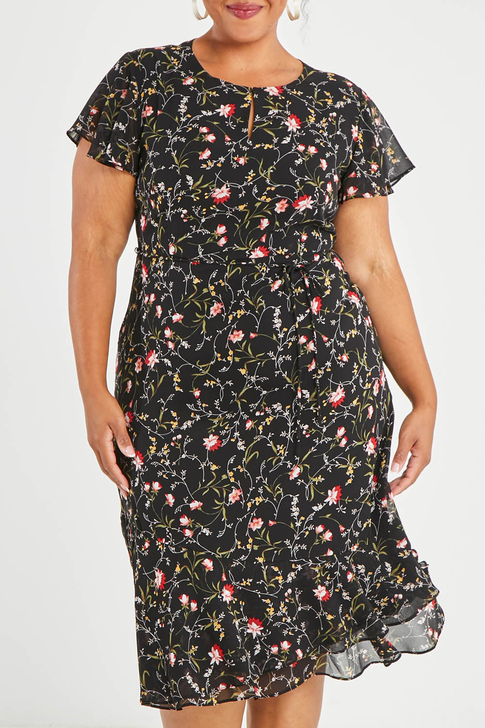 Model Alexis wearing size 16 of The Printed Chiffon Lined Dress in colour Botanical (Black), from the front, cropped image