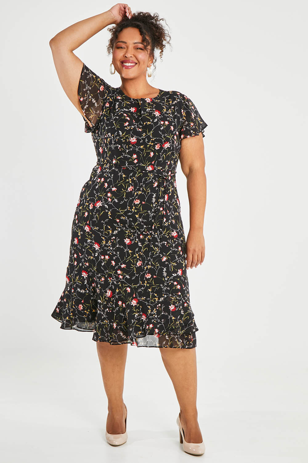 Model Alexis wearing size 16 of The Printed Chiffon Lined Dress in colour Botanical (Black), from the front, showing the whole outfit