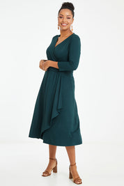 Model Noli wearing size 14 of The Bamboo Faux Wrap Dress in colour Deepgreen (Green), from the front, showing the whole outfit