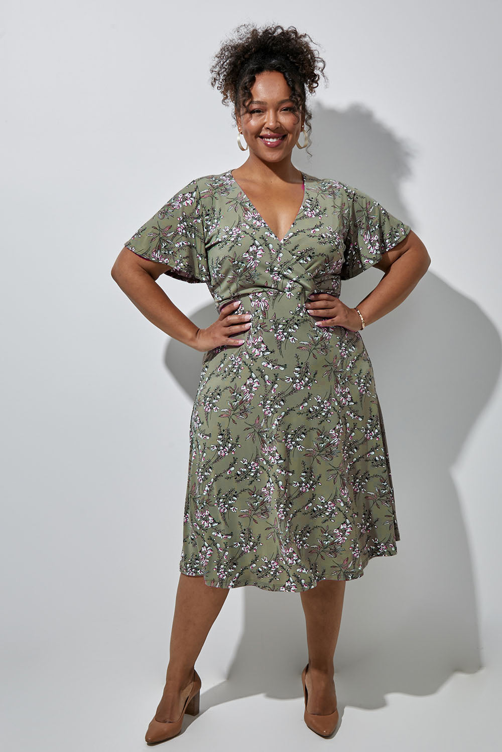 Model Alexis wearing size 16 of the Preloved The Printed Jersey Faux Wrap Dress in colour Fleur (Green), from the front, showing the whole outfit