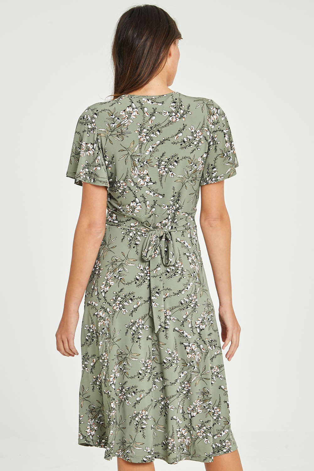 Model Madeline wearing size 10 of The Printed Jersey Faux Wrap Dress in colour Fleur (Green), from the back