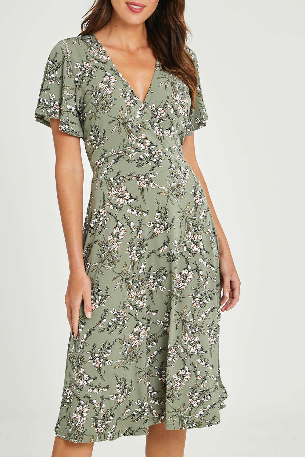 Model Madeline wearing size 10 of The Printed Jersey Faux Wrap Dress in colour Fleur (Green), from the front, cropped image
