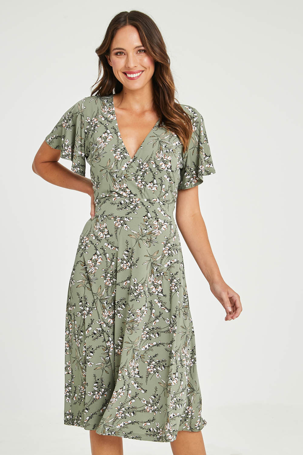Model Madeline wearing size 10 of The Printed Jersey Faux Wrap Dress in colour Fleur (Green), from the front, cropped image