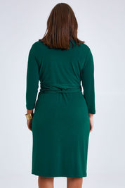 Model Monique wearing size 14 of the Belle Basic Wrap Dress in colour Pine (Green), from the back