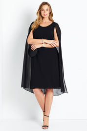Model Bree wearing size 14 of the Belle Cape Dress in colour Black (Black), from the front, showing the whole outfit