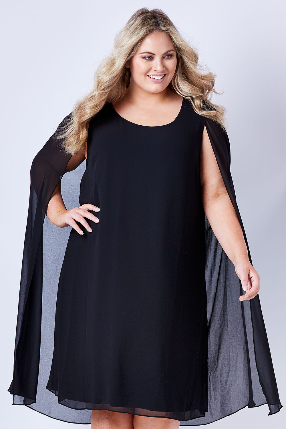 Model Sophie wearing size 20 of the Belle Cape Dress in colour Black (Black), from the front, cropped image