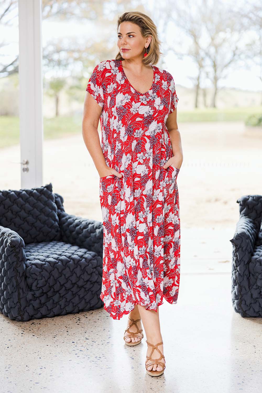 Model Fiona wearing size 16 of the Belle High Low Dress With Pockets in colour Redfloral (Red), from the front, showing the whole outfit
