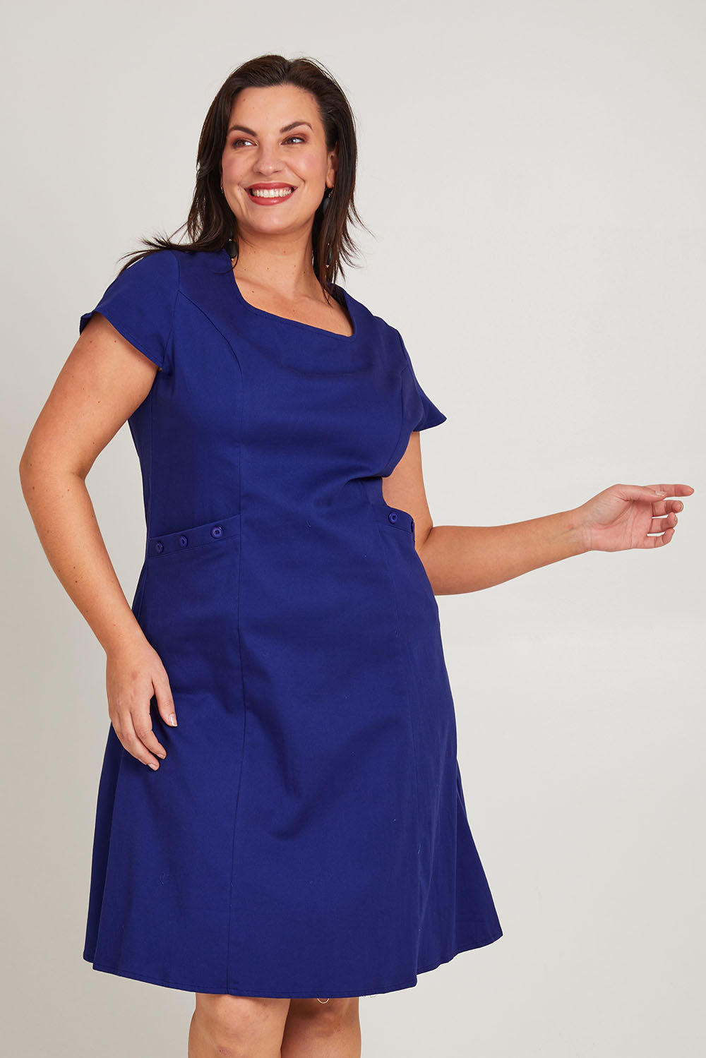 Model Poppy wearing size 16 of the Belle A Line Cotton Sateen Dress in colour Sapphire (Blue), from the front, cropped image