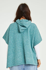 Model Laura wearing size M-L of the Keeping The Chill Out Poncho in colour Sea (Blue), from the back