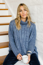 Model Tegan wearing size S-M of the Cool Breeze Cable Sweater in colour Denim (Blue), from the front, showing the whole outfit