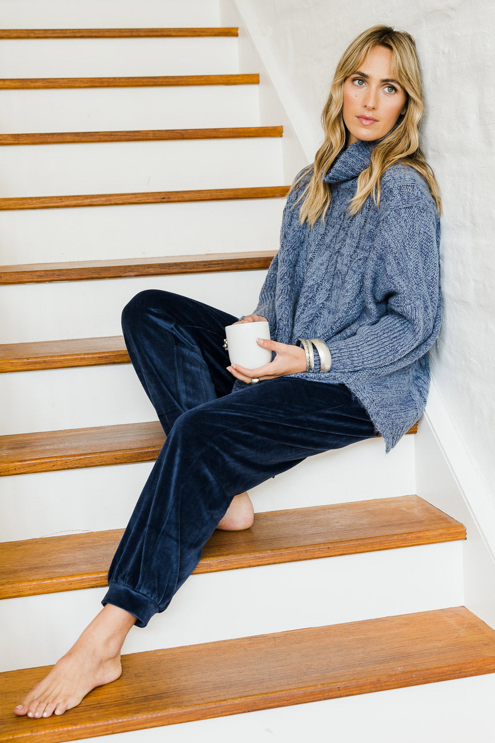 Model Tegan wearing size S-M of the Cool Breeze Cable Sweater in colour Denim (Blue), from the front, showing the whole outfit