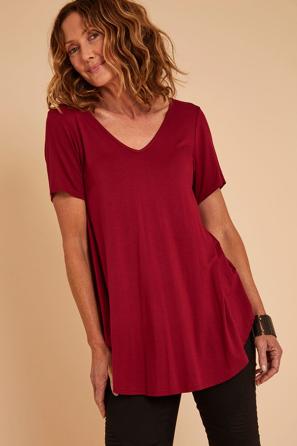 Model Emma wearing size 10 of the Softly Swinging Bamboo Tee in colour Ruby (Red), from the front, cropped image