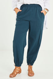 Model Terri-Leigh wearing size 14 of the Dawn Break Relaxed Pants in colour Ocean (Blue), from the front, cropped image