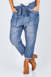 Model Laura wearing size 14 of the With My Tribe Pants in colour Denim (Blue), from the front, cropped image