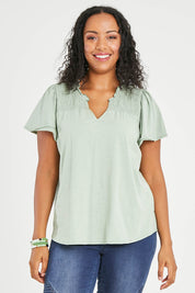 Model Noli wearing size 14 of the Shirred Butterfly Sleeve Tee in colour Sage (Green), from the front, cropped image