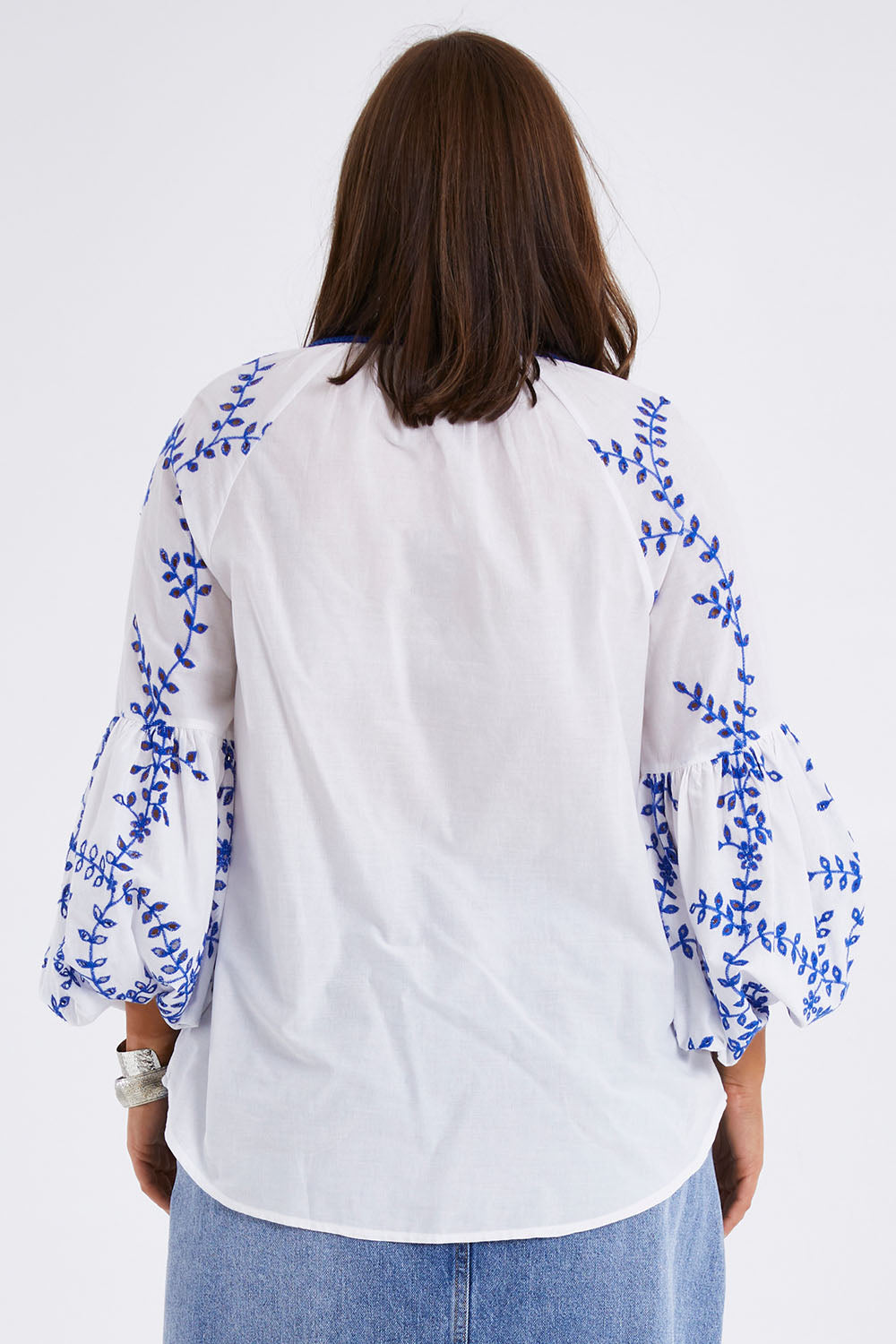 Model Monique wearing size 14 of the Feel My Vibe Embroidered Blouse in colour Whiteblue (White), from the back