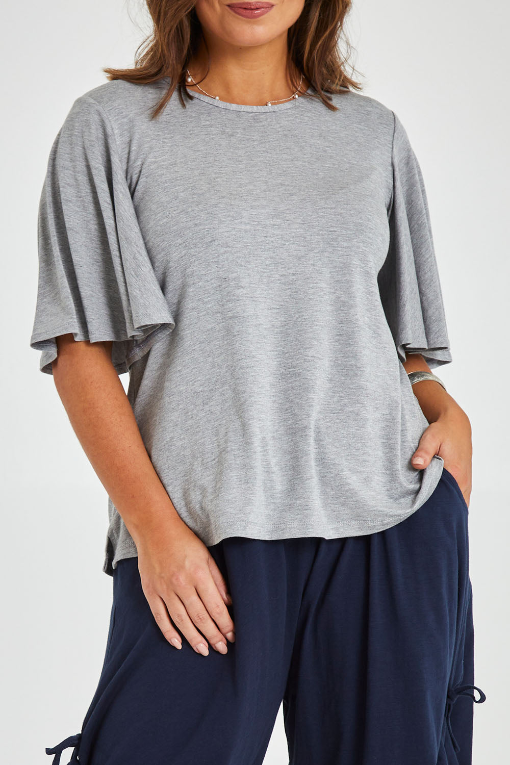 Model Monique wearing size 14 of the Flutter By Tee in colour Lightgrey (Grey), from the front, cropped image